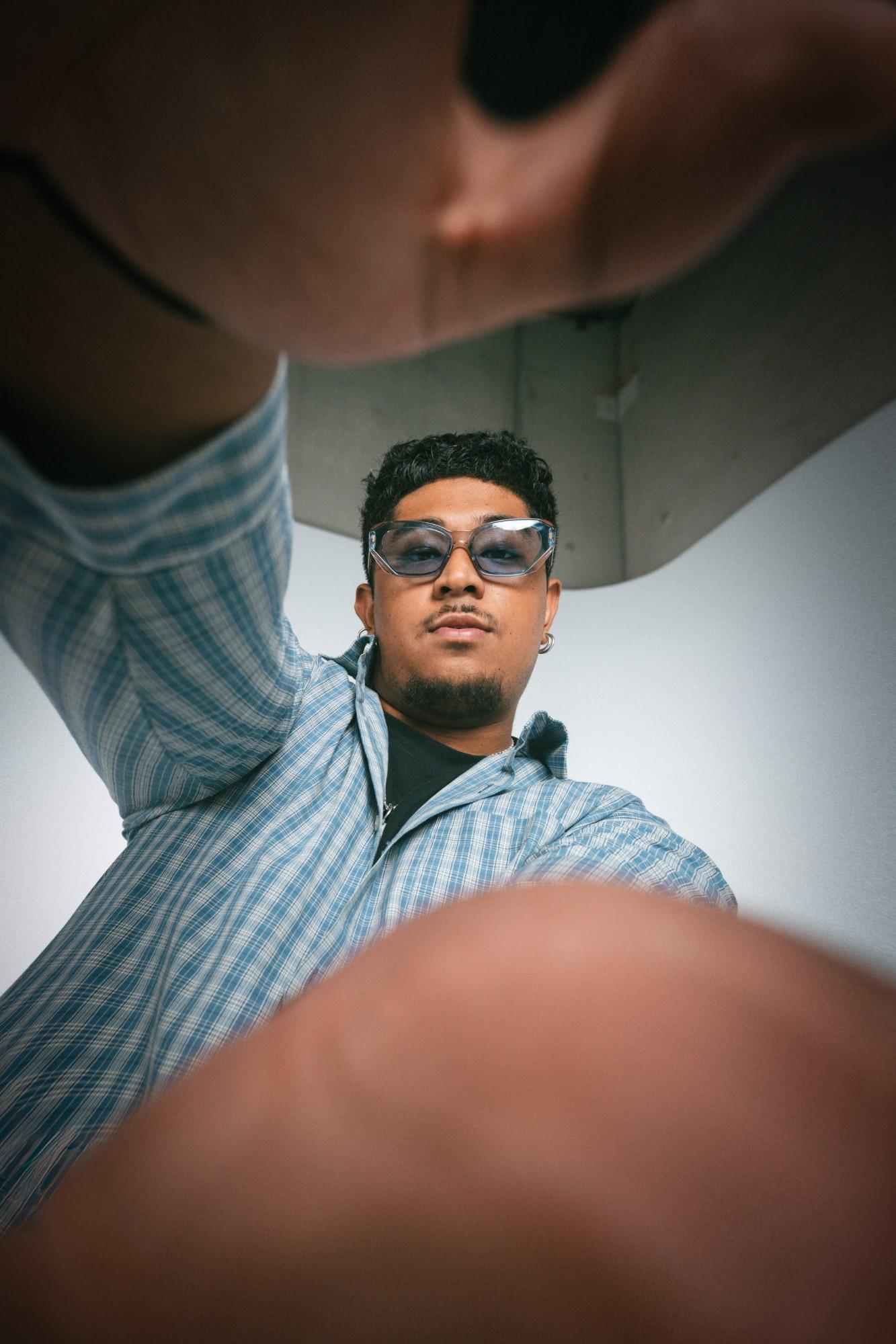 A young man from GenJ in a blue checked shirt, reaching towards the camera