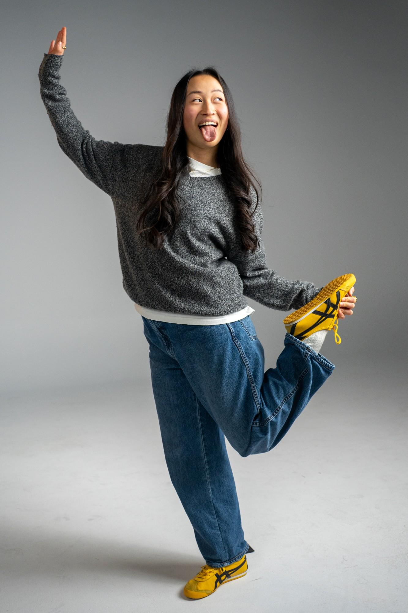 A young woman from GenJ in yellow sneakers, mid-pose and laughing